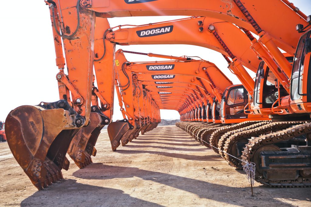 Several orange backhoes lined up in a row