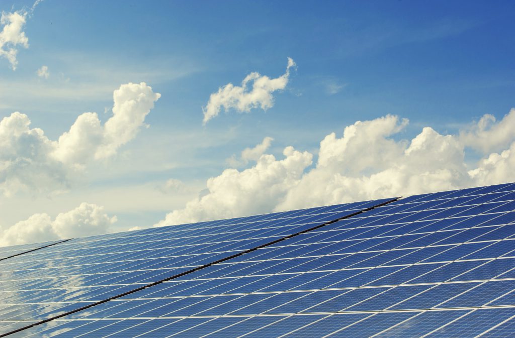 large blue solar panels with white clouds reflection